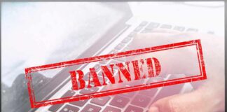 Red "Banned" stamp over a laptop keyboard.