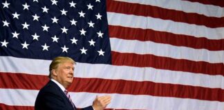 Man clapping in front of the American flag.
