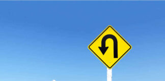 Yellow uturn sign against blue sky