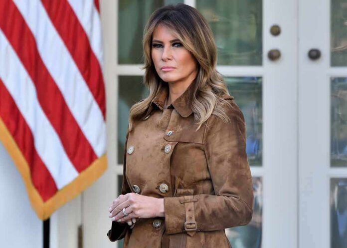 1572261598 featured image Woman in brown coat near American flag.