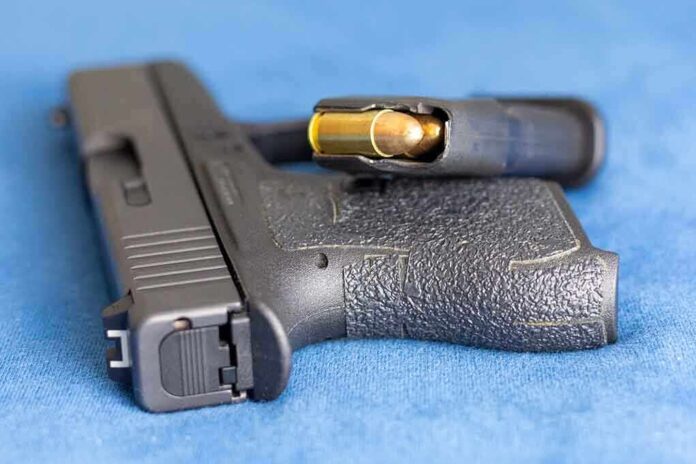 2159542825 featured image Handgun on blue fabric with visible bullet cartridge.