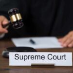 Judge with gavel and Supreme Court nameplate.