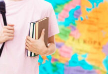 Person holding books in front of a colorful map