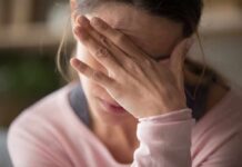 Woman covering face with hand looking stressed
