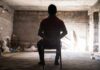 Person tied to chair in dimly lit room