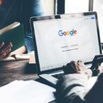 Laptop on Google homepage person reading a book