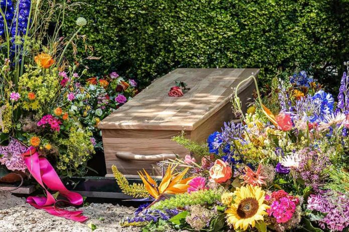 2191683741 featured image Wooden coffin surrounded by colorful flowers at funeral.
