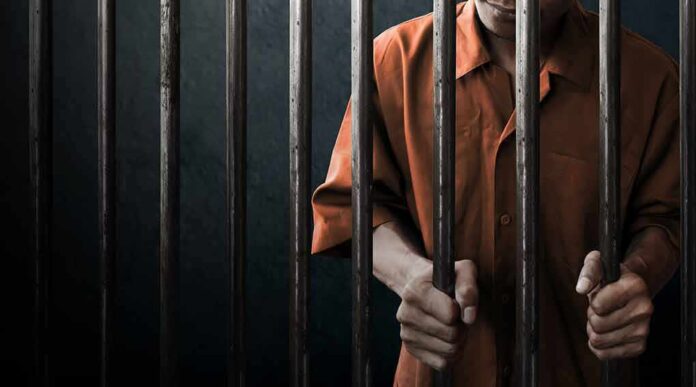 744470836 featured image Person in orange shirt behind jail bars