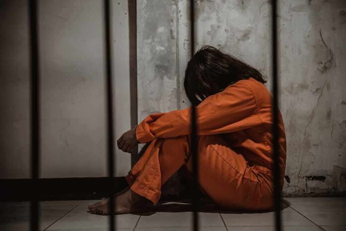 1383143171 featured image Person in orange jumpsuit sitting behind bars head down
