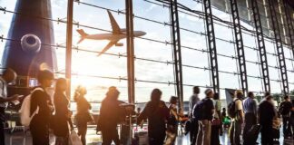 Passengers waiting at airport gate with airplane outside window