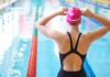 Swimmer adjusting cap near an indoor pool