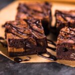 Chocolate brownies with drizzled chocolate on parchment paper