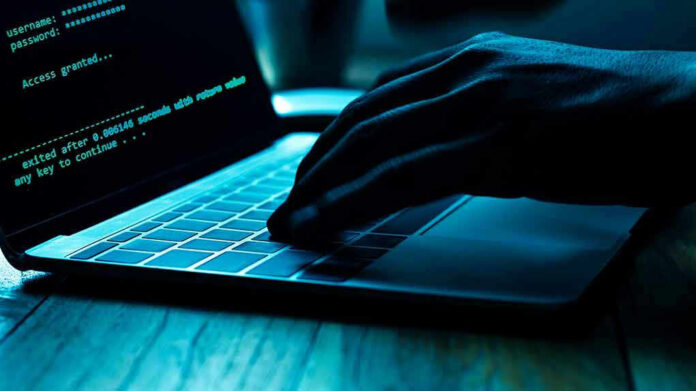 Hand typing on laptop with code on screen