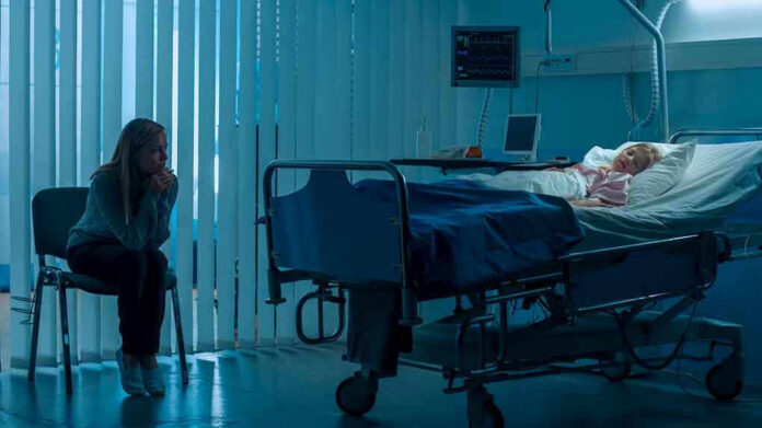 Woman sitting beside hospital bed at night