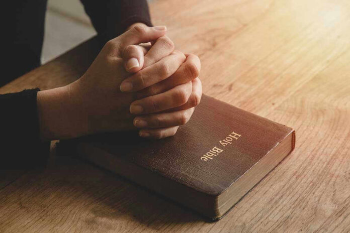 Hands praying on a Bible