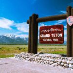 Grand Teton Rabies Alert — Hundreds At Risk! Entrance sign for Grand Teton National Park with mountains in the background