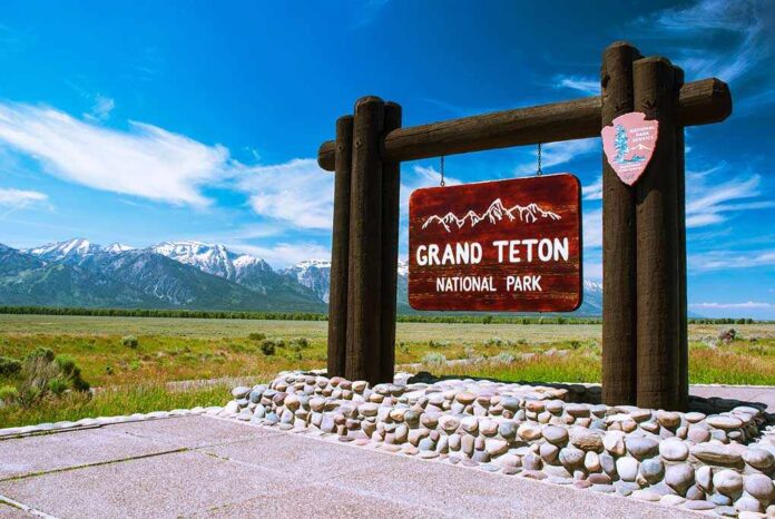 Entrance sign for Grand Teton National Park with mountains in the background