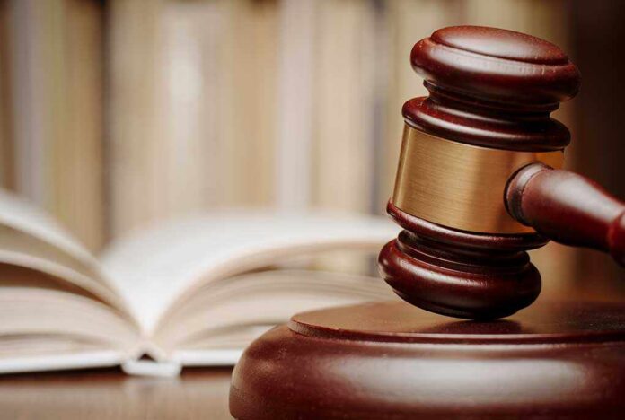 A wooden gavel resting on a sound block with law books in the background