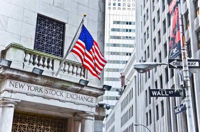 Facade of the New York Stock Exchange with an American flag and Wall Street sign