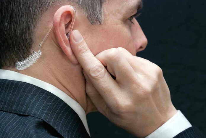 172646540 Man wearing an earpiece, touching his ear.