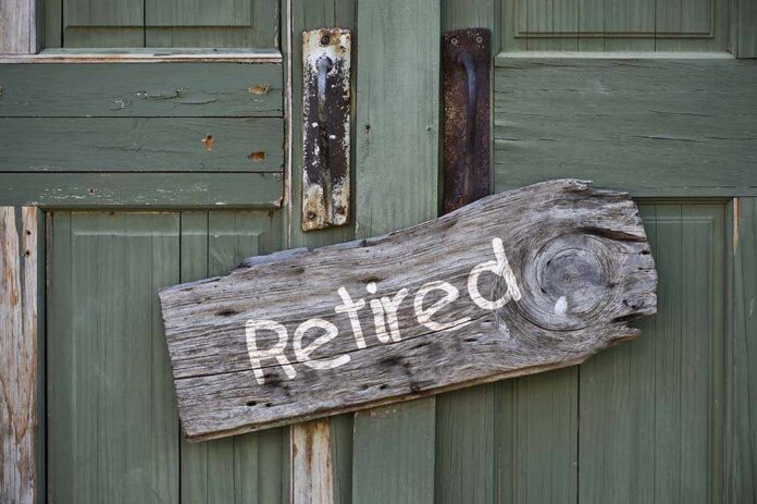 Weathered wooden sign reading Retired hanging on a green door