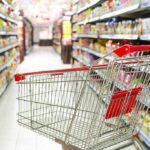 Corporate Shake-Up: Major Brand SPLITS Company A shopping cart in a grocery store aisle filled with colorful products