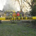 Burning Man HOMICIDE — Peace Shattered in Desert Chaos Yellow police tape marking a restricted area at a fire scene with firefighters in the background