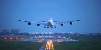 An airplane approaching the runway at night with landing lights illuminated