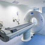 A CT scanner in a hospital room with medical equipment nearby