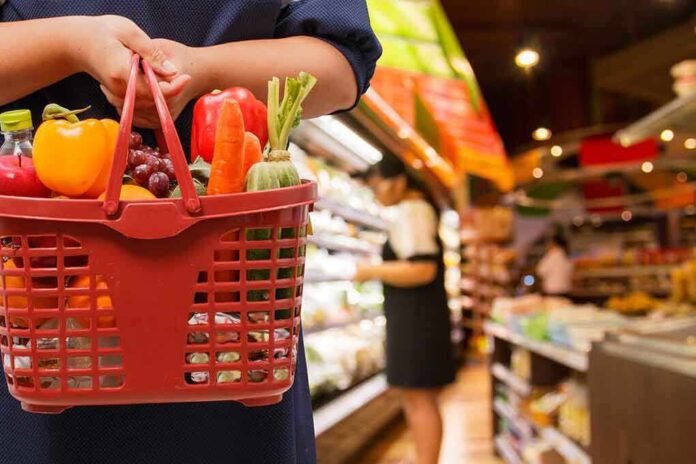 shutterstock_233691502.jpg Person holding a basket filled with colorful vegetables in a supermarket