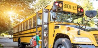 A child with a backpack boarding a yellow school bus