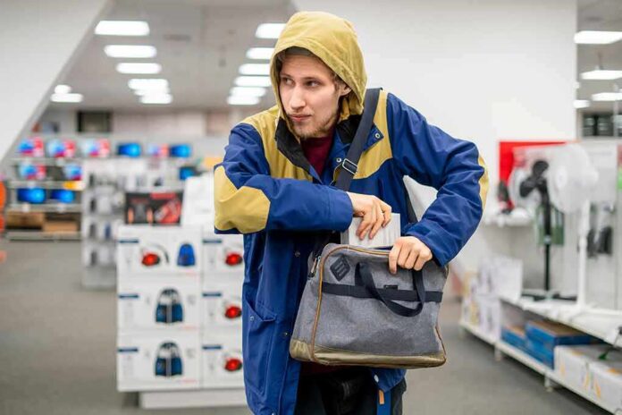 A man in a jacket appearing to conceal a bag in a retail store