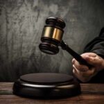 A judges gavel poised to strike a sound block