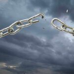 A broken metal chain against a stormy sky
