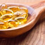 Golden omega-3 capsules in a wooden spoon