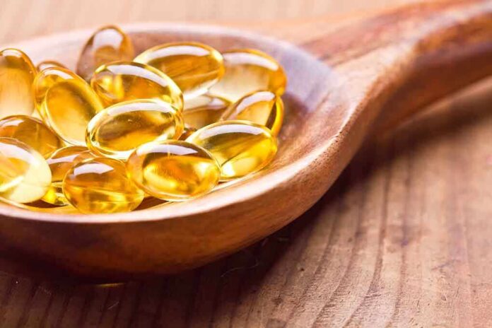 Golden omega-3 capsules in a wooden spoon