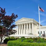 Supreme Court building with American flag and surrounding greenery