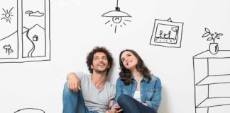 A couple sitting on the floor against a wall with playful illustrations