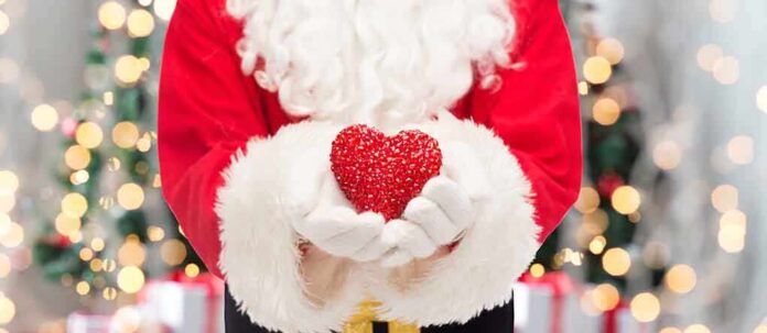 shutterstock_224223199.jpg Santa Claus holding a red heart in front of a festive background