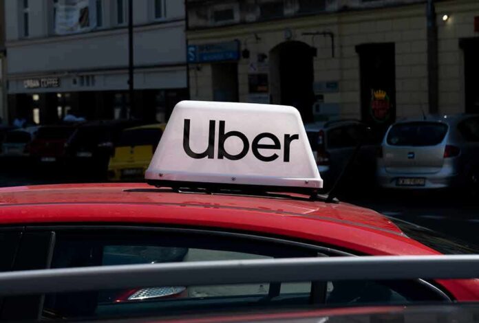 Uber sign on top of a red taxi in an urban setting