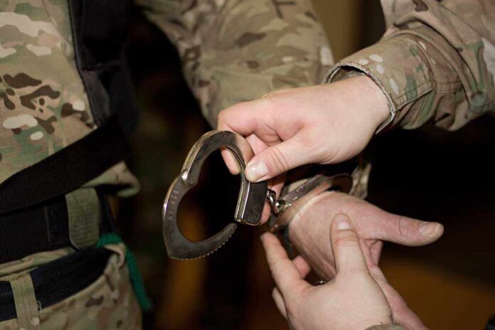 shutterstock_97315970.jpg A military personnel placing handcuffs on an individual
