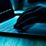 ICE Agents’ Identities Exposed in Shocking Breach Hand typing on laptop with code on screen.