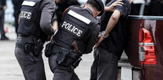 Police officers arresting a handcuffed person.