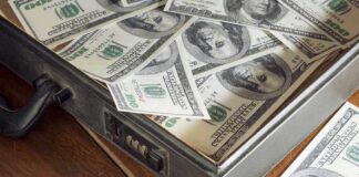 A briefcase filled with hundred dollar bills on a wooden surface