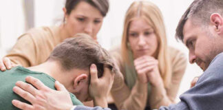 Group comforting a distressed person with hand on shoulder.