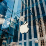 Apple store with glass facade and city reflections.
