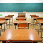 Empty classroom with desks and a chalkboard.