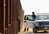 14,000 Hires: ICE’s Controversial Expansion Plan Border patrol agents near a tall metal fence.