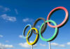 Olympic rings sculpture against blue sky.