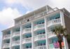Exterior view of a beachfront hotel with balconies and colorful towels hanging